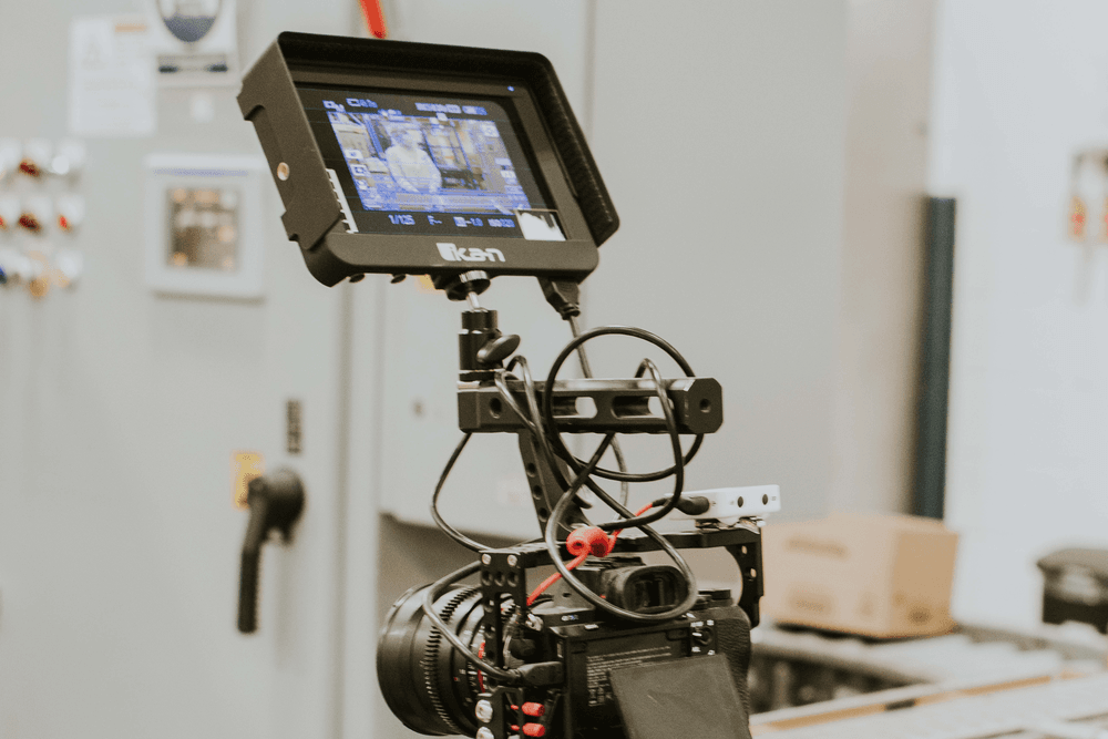 Camera monitor displaying a factory worker being filmed on a manufacturing floor.