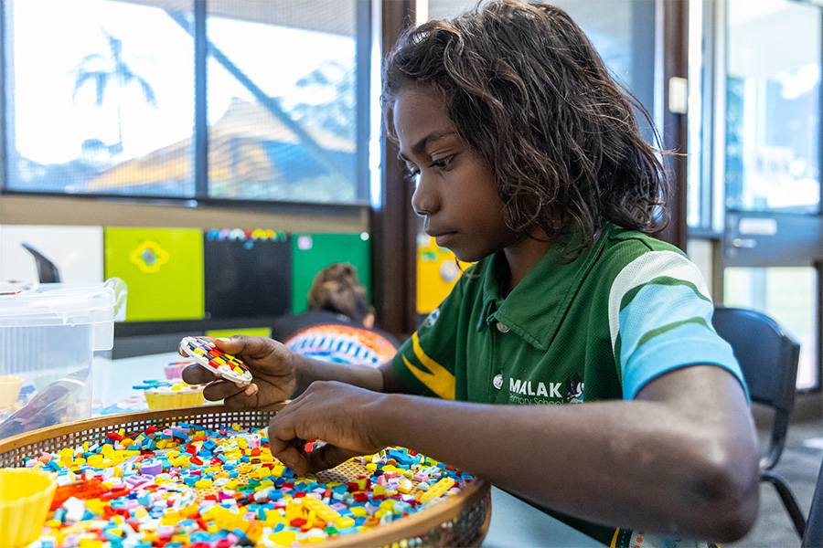An Indigenous child seated at a table engaging in a scientific activity using colourful counters.