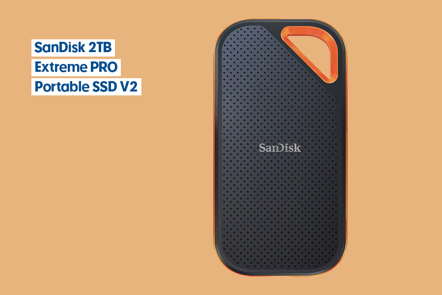 SanDisk 2TB Extreme PRO Portable SSD V2 with black perforated exterior and orange accent corner, displayed on a peach background.