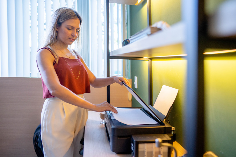 A person using a multifunction printer to scan a document in a small office setting.