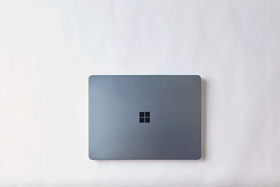 A series of images showing hands opening and closing a silver Microsoft Surface Laptop Copilot+ PC with a blue keyboard and trackpad, set against a white background.