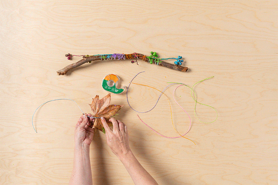 A series of images showing the process of sticking the painted lengths of twine to the painted leaves, then tying the other end of the twine pieces to the stick to complete the leaf mobile.