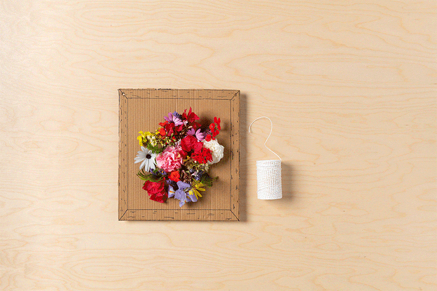 A series of images showing the process of adding twine to each top corner of the finished cardboard flower wall art to create a hanger, and then hanging the art.