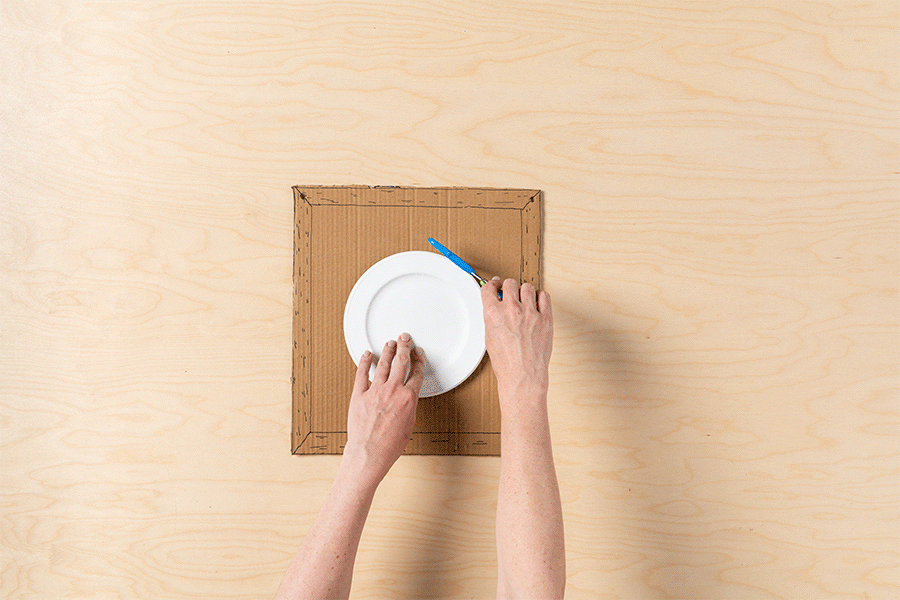 A series of images showing the process of scoring a circle onto a piece of cardboard and piercing holes within the circle using scissors.