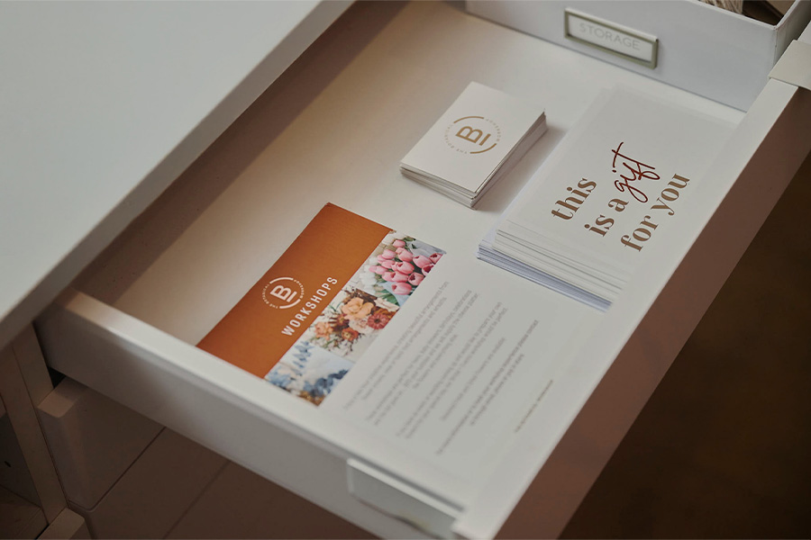 An open desk drawer with branded stationery for The Botanical Workshop, including workshop flyers, business cards and gift cards.