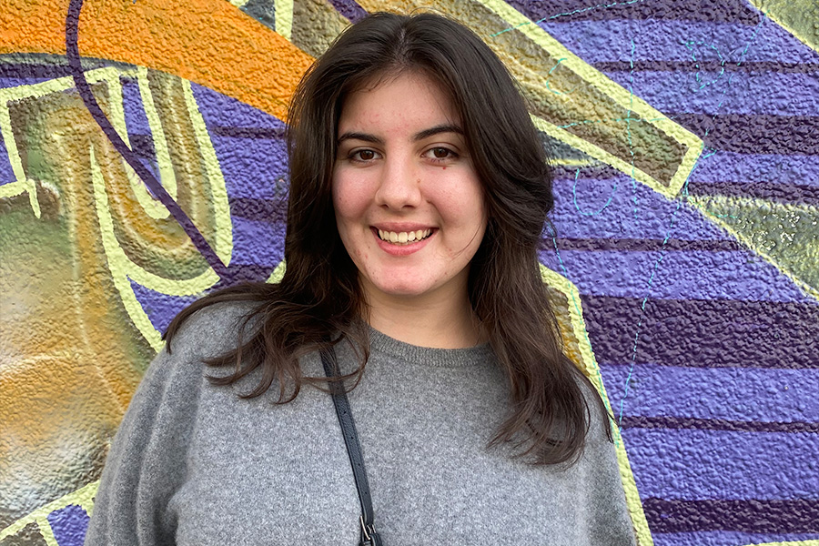 A close-up shot of Mia Sinosic-Cass standing in front of a colourful graffiti wall.