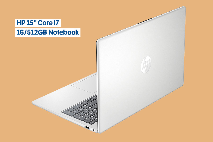 The HP 15-inch Core i7 16/512GB Notebook, pictured slightly open and positioned at an angle showing its light grey outside casing and black keyboard, on an orange background.
