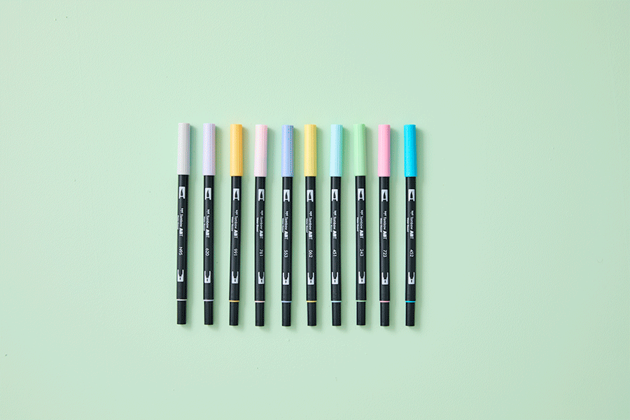 A selection of Christmas gifts for creative people, shown on various brightly coloured backgrounds. Products include things like brush pens and a portable box easel. 