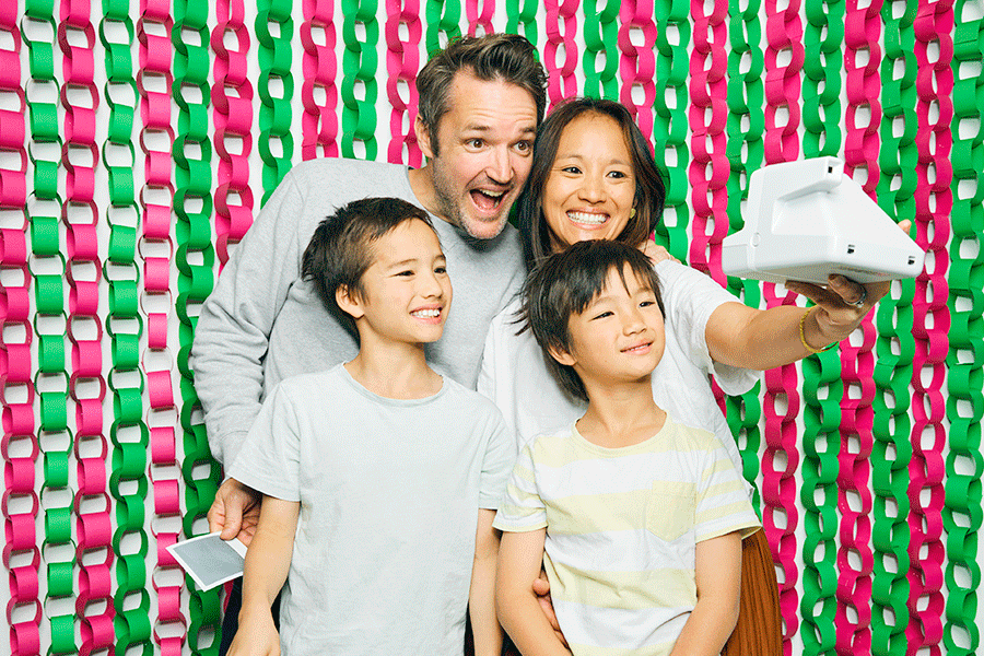 A series of images showing a family of four posing for Christmas photos. Everyone is bunched up close together, making a variety of poses and expressions to make a fun family photo.