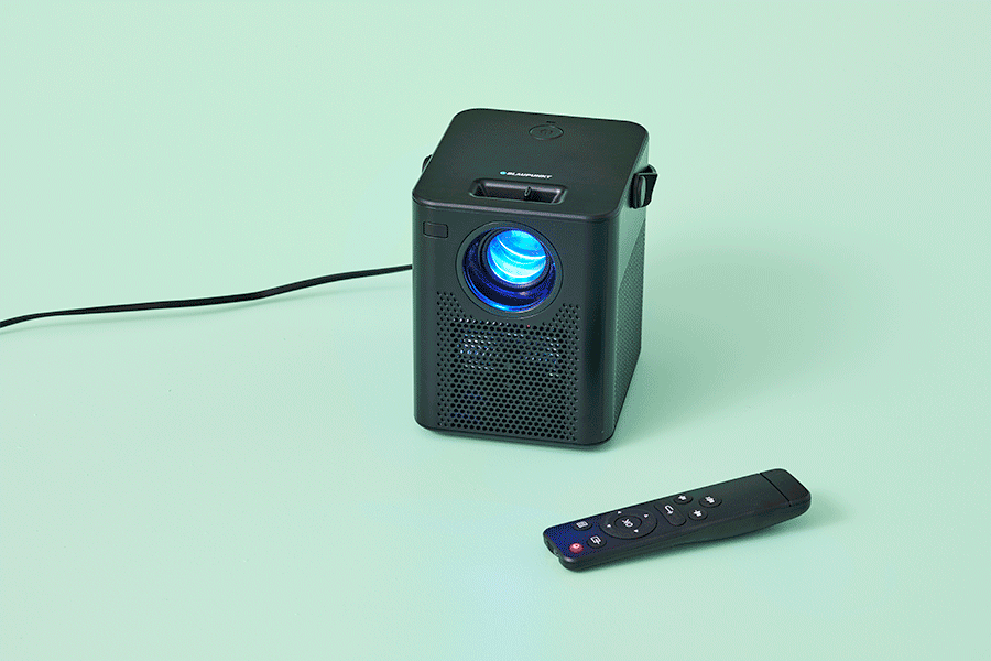 A selection of Christmas gifts for entertainment lovers, shown on various brightly coloured backgrounds. Products include a projector, wireless speaker and digital camera.