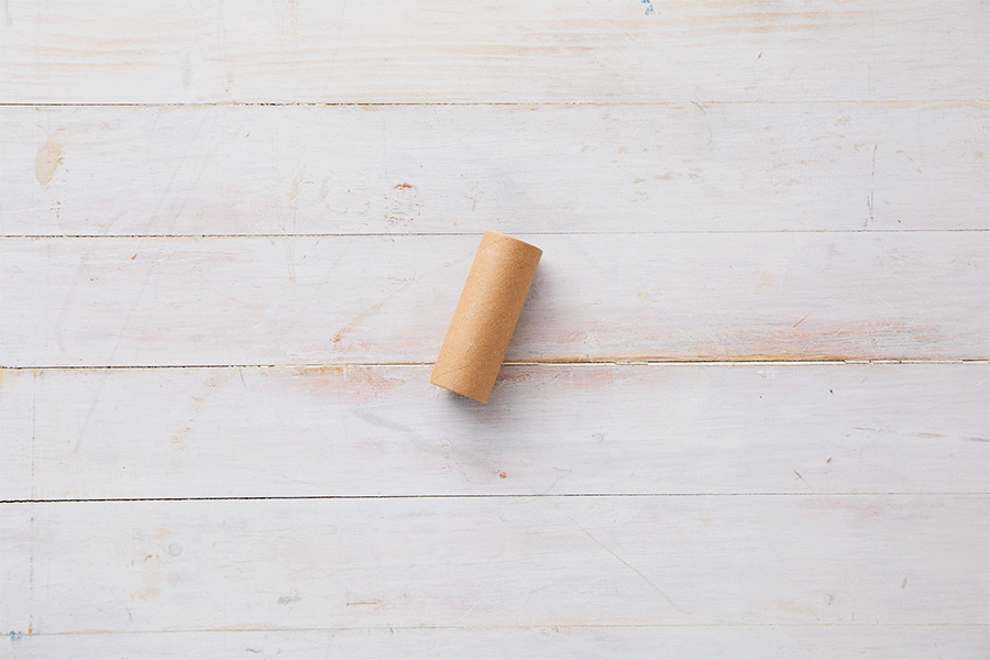 A series of images demonstrating Steps 1 to 3 of making cardboard roll stackers, showing a hand cutting small vertical slits into the ends of a cardboard tube with scissors.