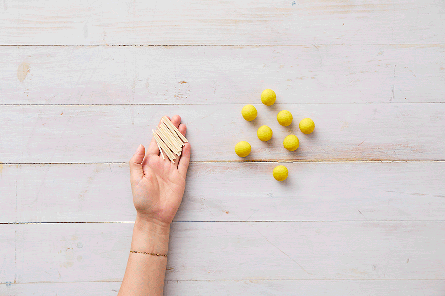 A series of images demonstrating Step 2 of making matchstick structures, showing hands pushing wooden matchsticks into balls of yellow playdough, connecting them together to create a 3D square structure.
