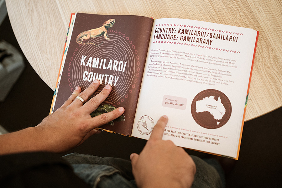 Hands holding an open book about Kamilaroi/Gamilaroi Country and Gamilaraay language, with title page, pronunciation guide and a map of Australia highlighting the region.