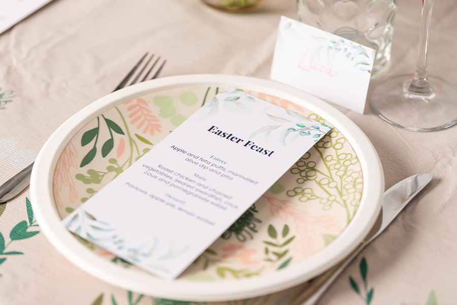A place setting featuring a floral plate with a menu and place card made using Little Boy Blue Officeworks template, which features gumleaves and native florals.