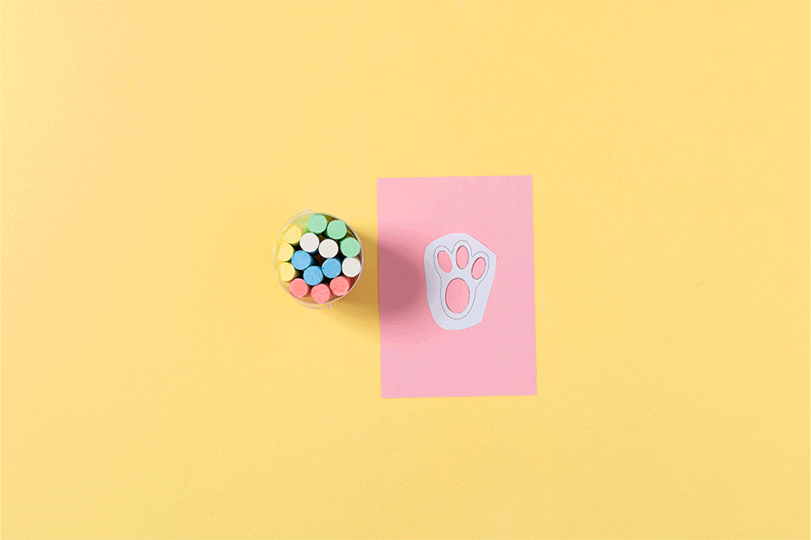 A series of images showing how to create bunny footprints drawn onto paper as an Easter holidays idea. This example uses a cut-out footprint paper stencil, pink paper and blue chalk.