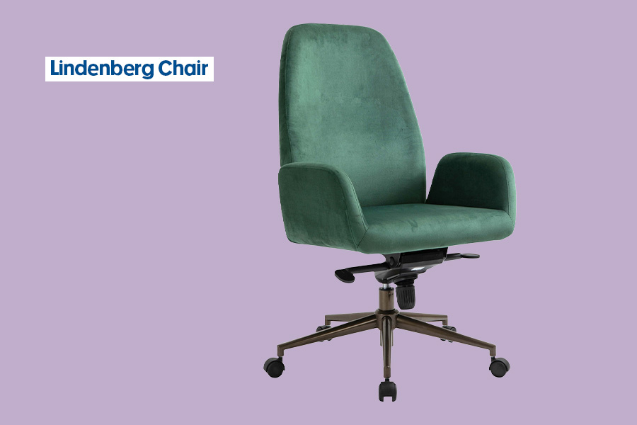 The Lindenberg desk chair in ‘Velvet green’, with a forest-green velvet high back, padded arms and seat on a bronze base with black castors, shown against a purple background.