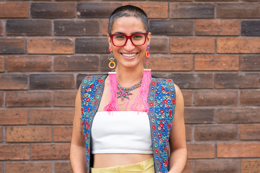 Zee Heart smiling at camera while standing in front of textured brick wall.