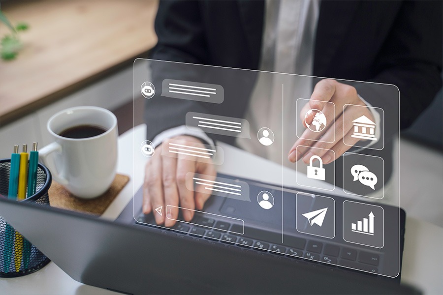 A person in business attire typing on a laptop with a holographic digital interface displaying icons for security, messaging and data analytics.