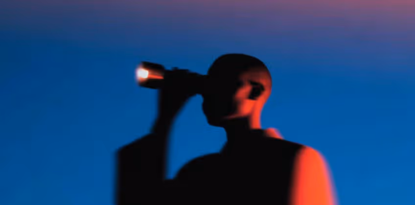 Silhouette of a person holding a small light source against a blue and purple gradient background.