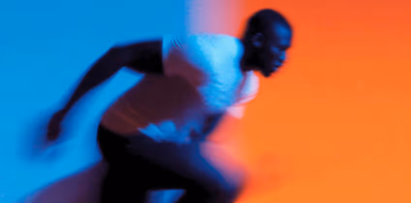 Blurred image of a person running against a blue and orange background.