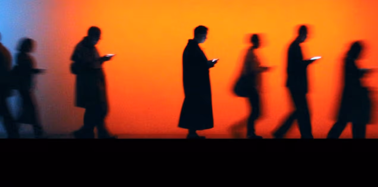 Silhouettes of people walking while looking at their smartphones against a gradient orange and blue background.