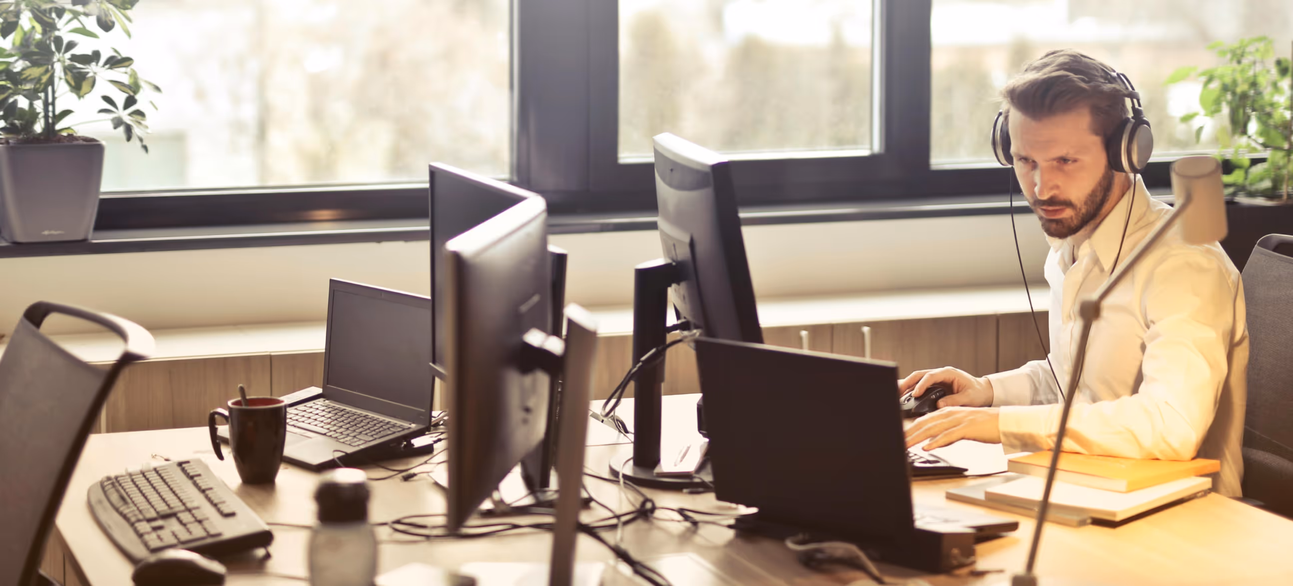 a man with headphones sitting at his desk and working on a computer 