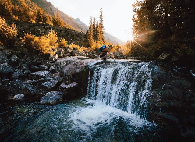 Hiker filtering water from waterfall