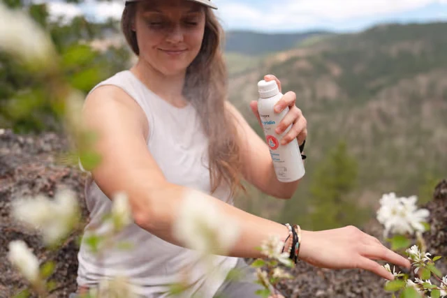 Woman spraying herself with bug spray