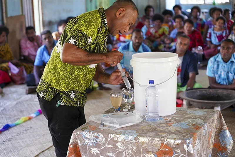 A man using a water filter in front of a group