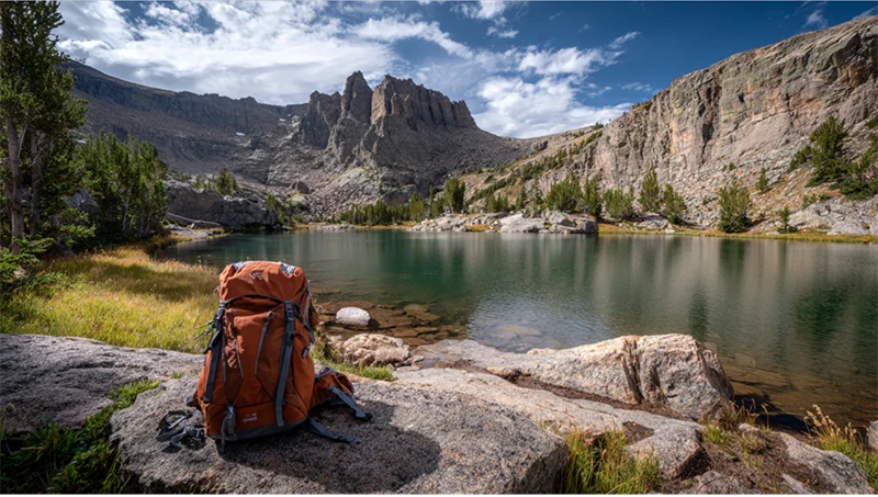 A backpack on a rock next to a lake.