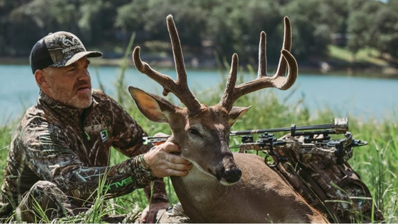 A man with a buck and hunting gear.