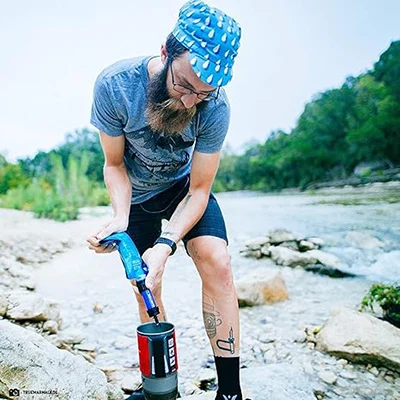 Gentleman filtering water from a Sawyer mini water filter by the river