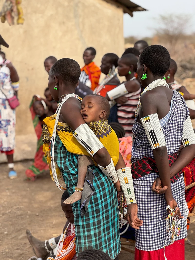 A woman carrying a baby on her back walking with other village people