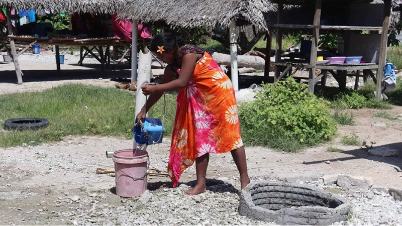 Girl fetching well-water to wash dishes