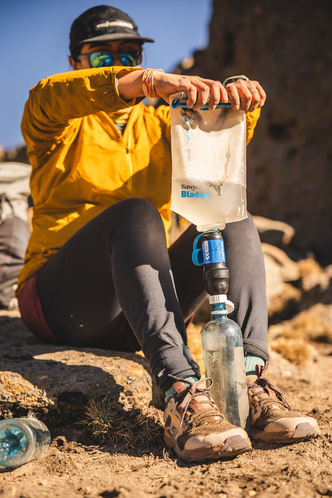 Woman using a Sawyer filter with a CNOC bag to filter water