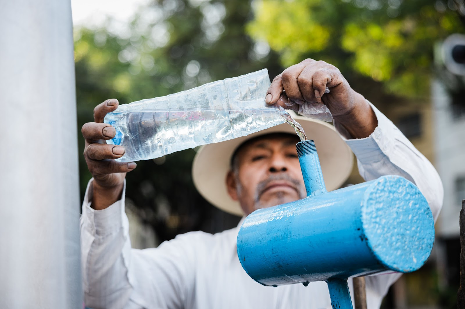 Man pouring water from a plastic bottle into a metal pipe