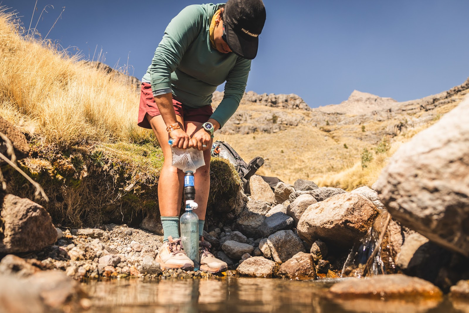 Woman squeeze filtering her bottle in the desert at a water source