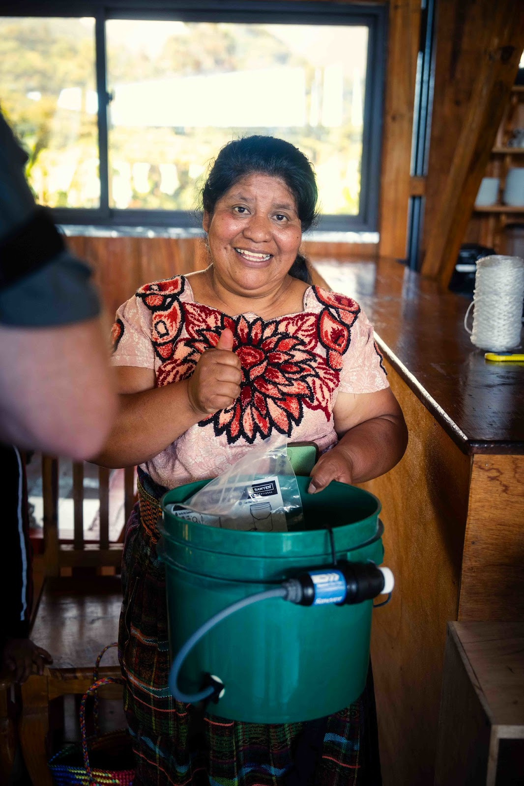 woman giving a thumbs up holding a sawyer bucket filtration system