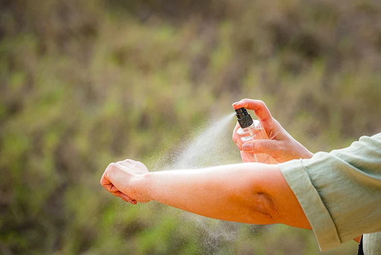 Insect repellent being sprayed on an arm.