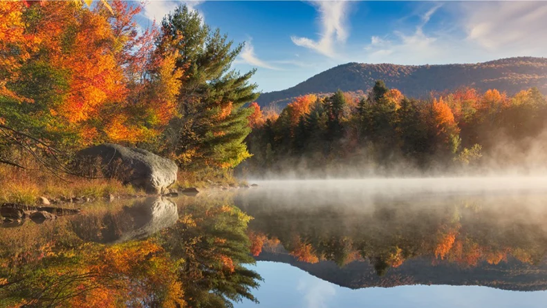 A lake surrounded by trees in the fall.