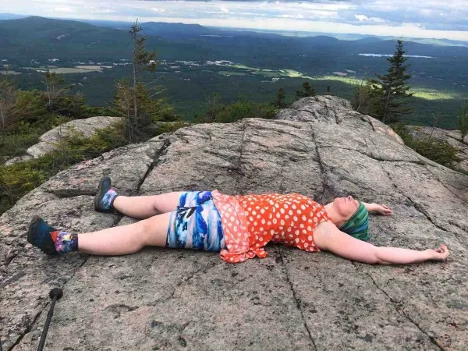 A person laying on a rock.