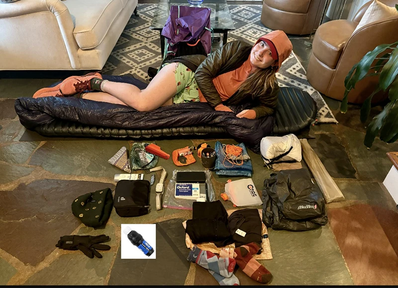 A person laying in front of camping gear.