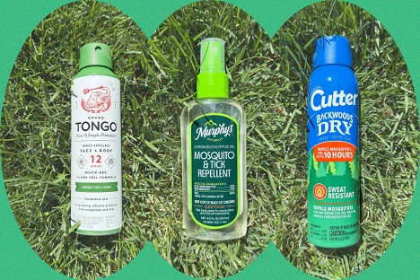 Three bottles of bug spray on grass.