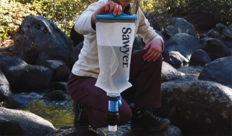 A Sawyer Squeeze Filter with a Cnoc bag being held.