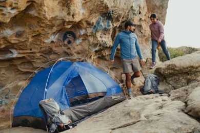 Two people on rocks near a tent.