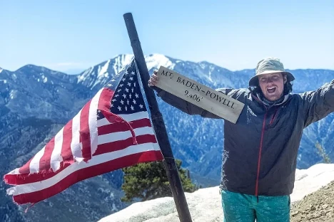 A person with a trail sign by an American flag.