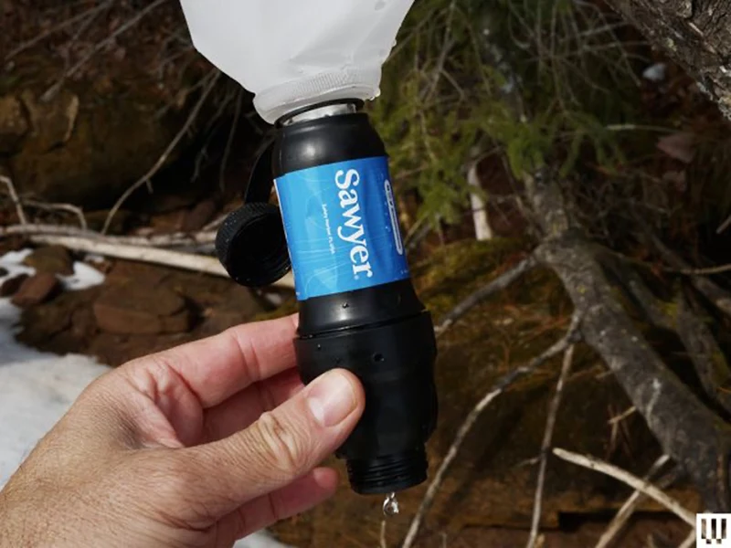 A hand holding a Sawyer Squeeze filter.