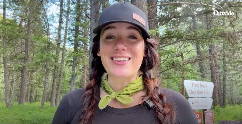A lady wearing a hat in the woods.