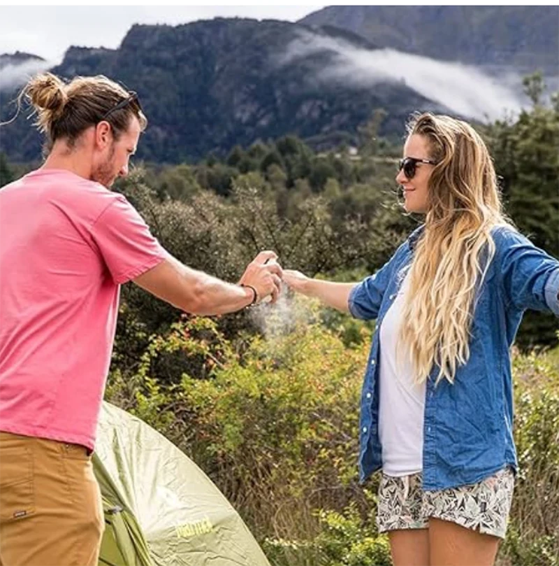 A man spraying a woman with Sawyer Picaridin spray.