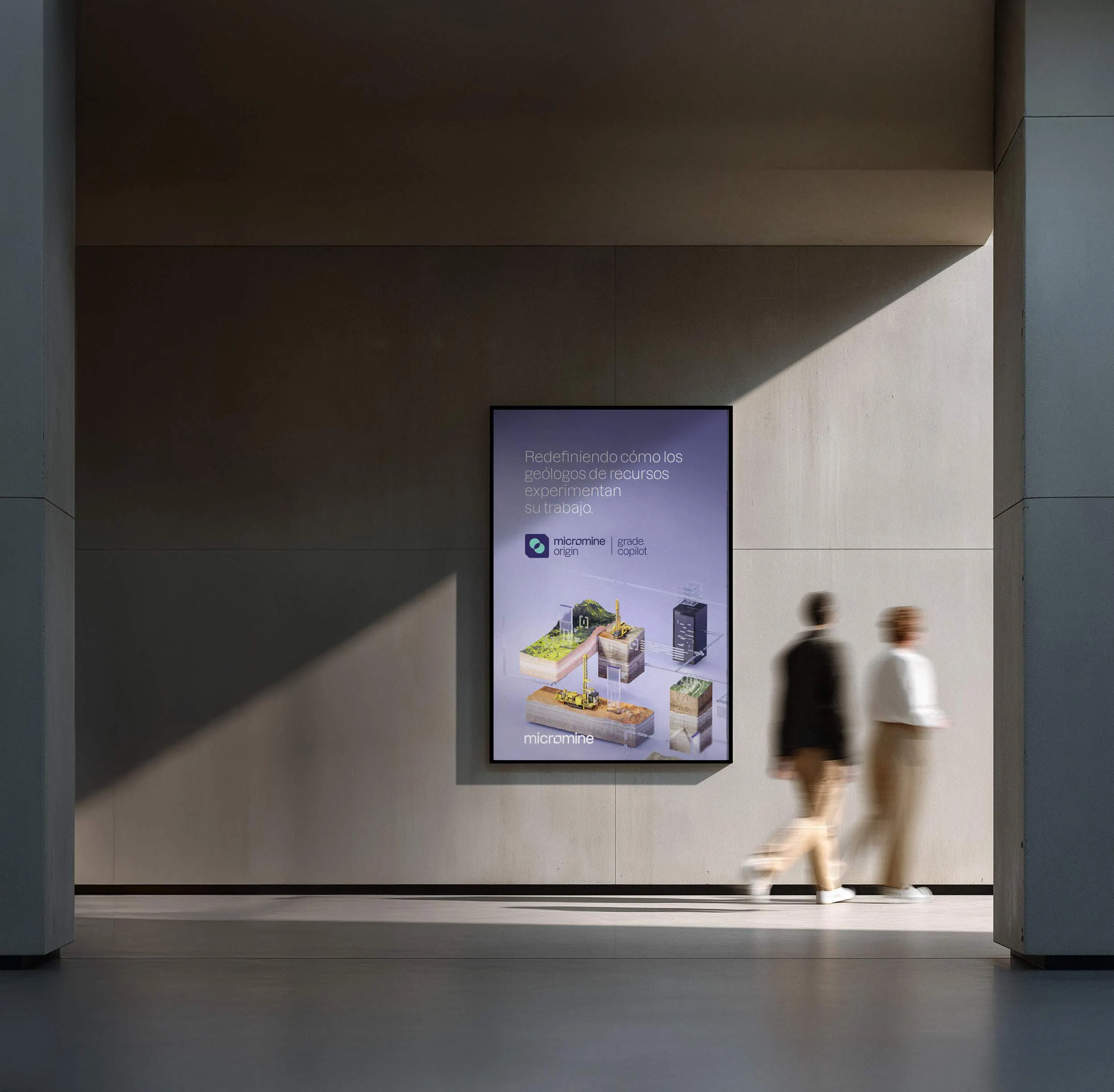 Minimalist modern hallway with light and shadow patterns on the wall and a digital display showing a mining technology advertisement in Spanish as two blurred people walk past.